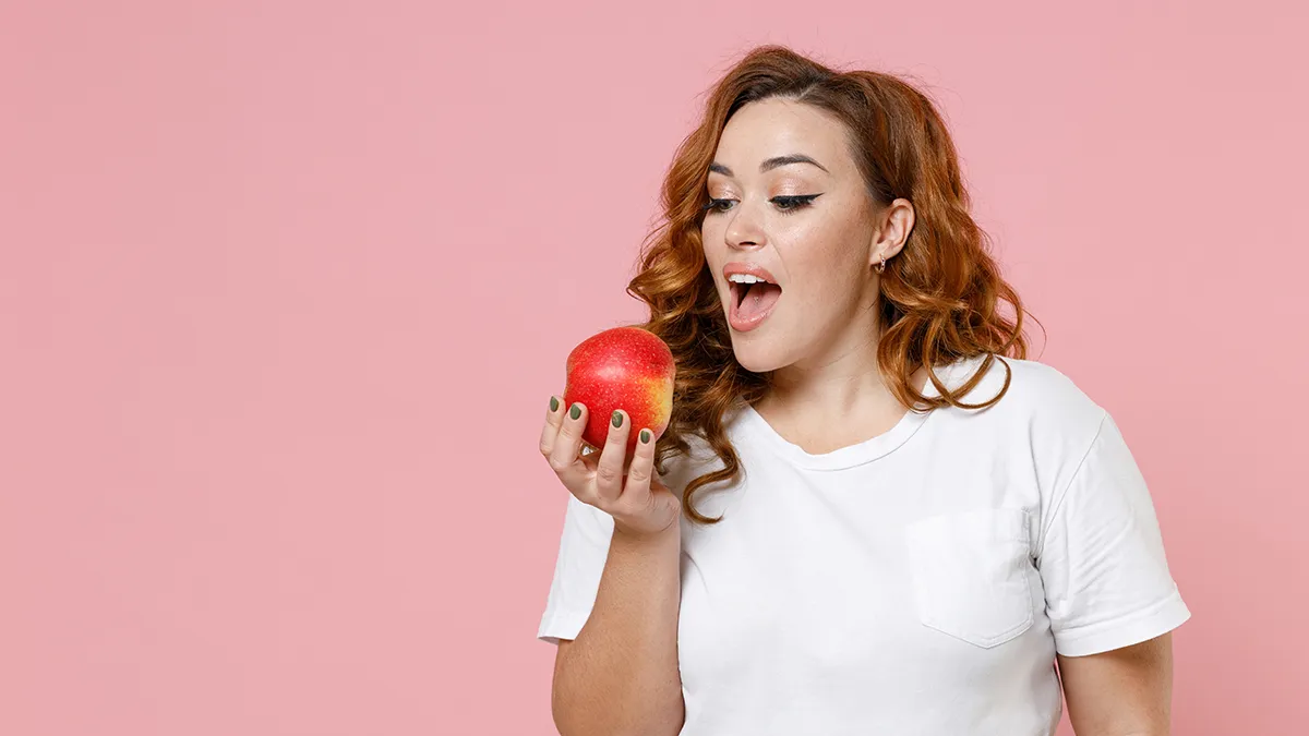 Beautiful woman with PCOS eating an apple